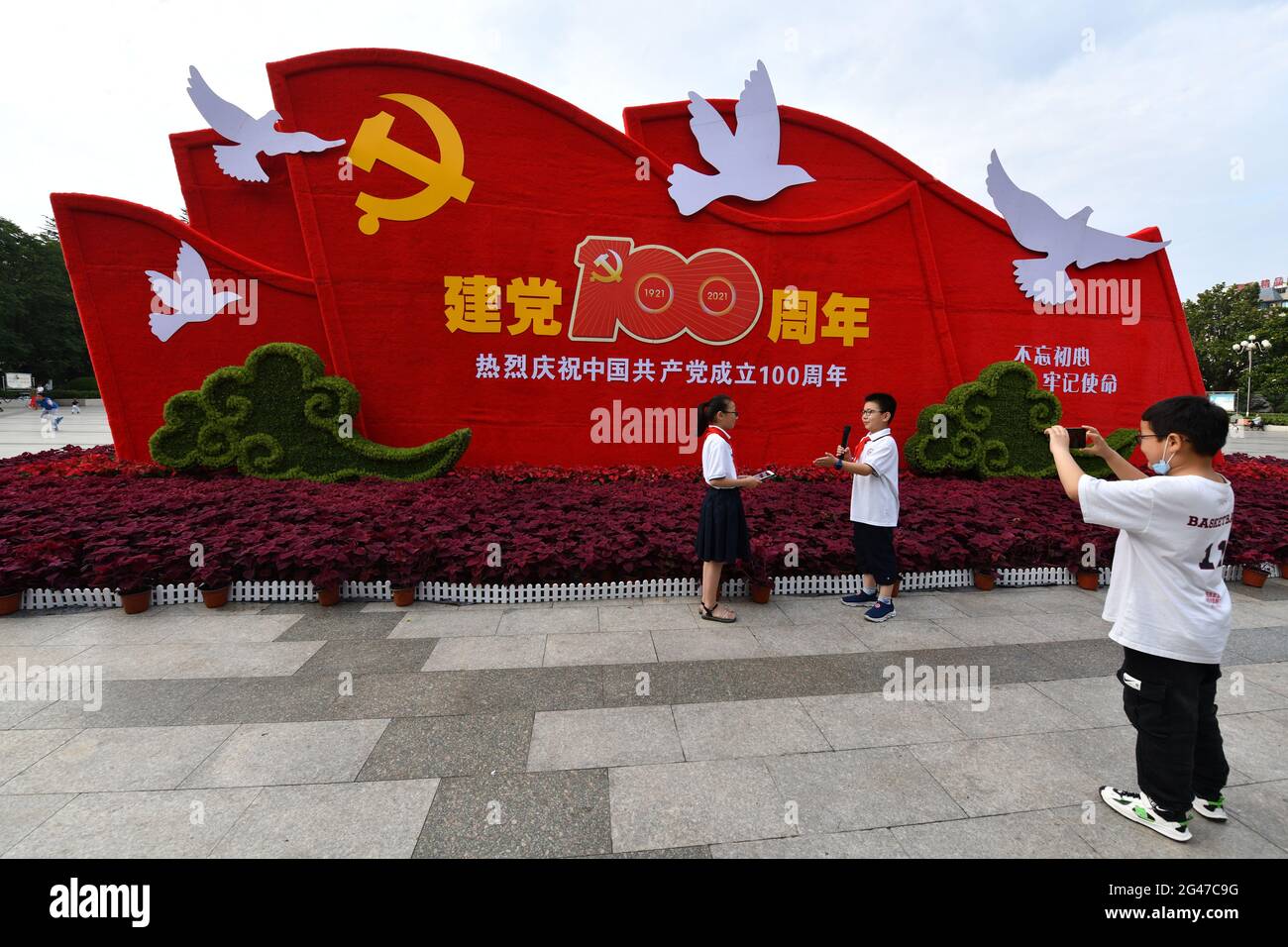 Fuyang, China. 19th June, 2021. Pupils wearing red scarves shoot videos before a sign marking the 100th anniversary of the founding of the Communist Party of China.As July 1 approaches, all parts of China are creating a 'red atmosphere' to celebrate the 100th anniversary of the founding of the Communist Party of China. Credit: SOPA Images Limited/Alamy Live News Stock Photo