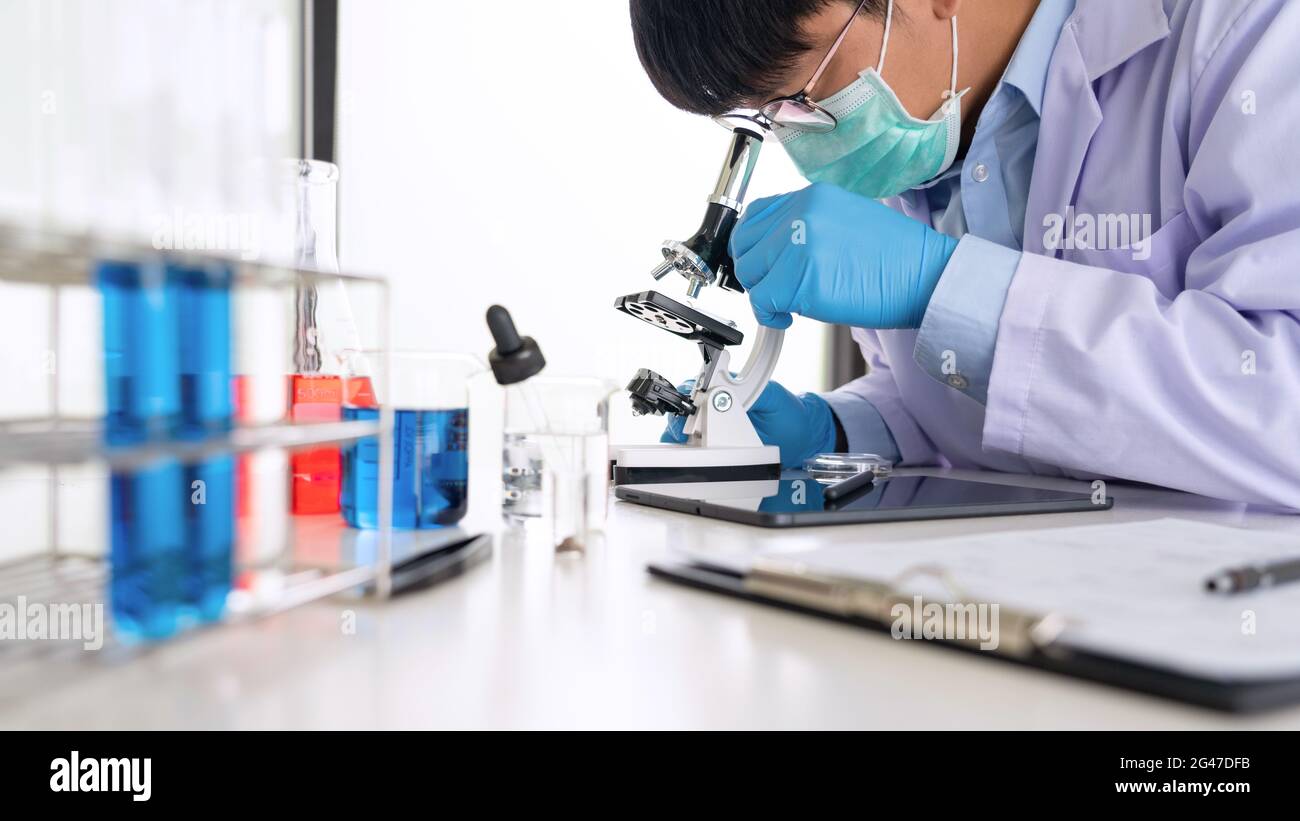 Young Asian scientist Working looking through a microscope doing ...