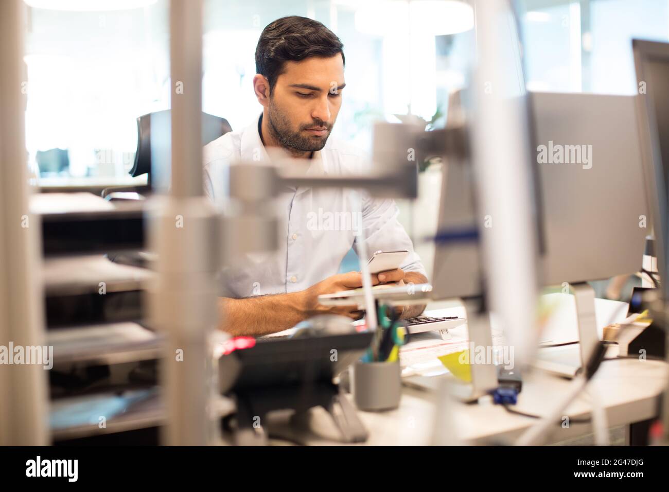 Businessman using mobile phone at desk in office Stock Photo