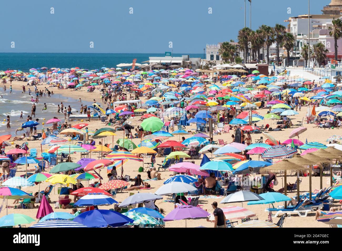 Chipiona, Cadiz, Spain - June 13, 2021: Chipiona beach full of tourists with umbrellas enjoying a sunny day Stock Photo