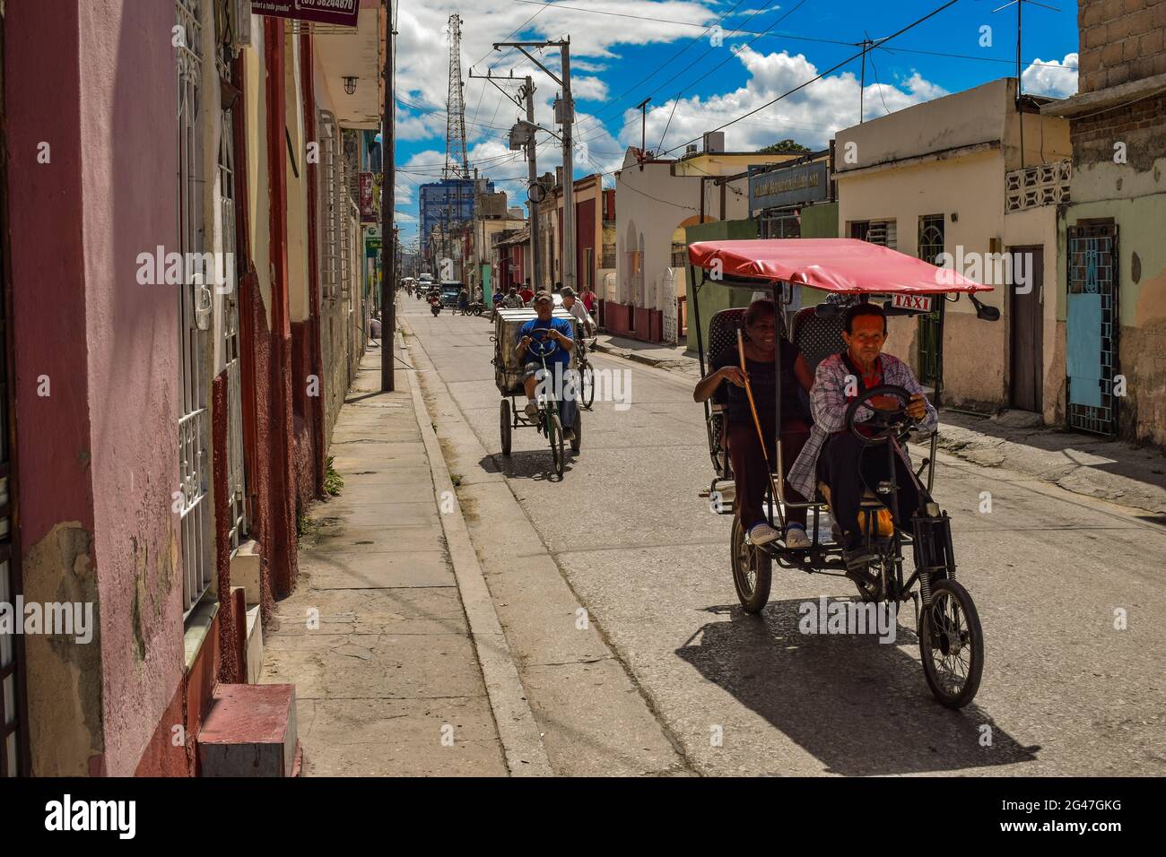 Bici-taxi driving down a backstreet in Holguin, Cuba Stock Photo