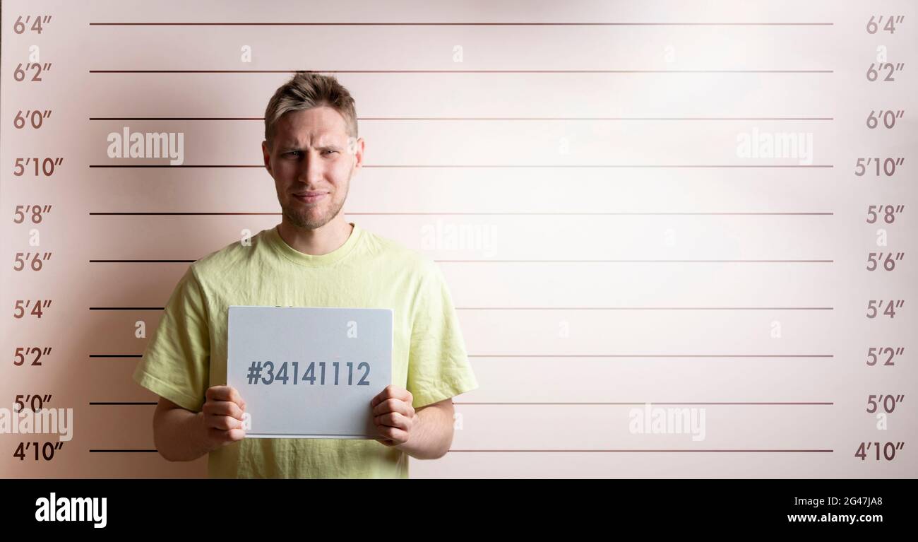 arrested prisoner young man holding a placecard in front of the height