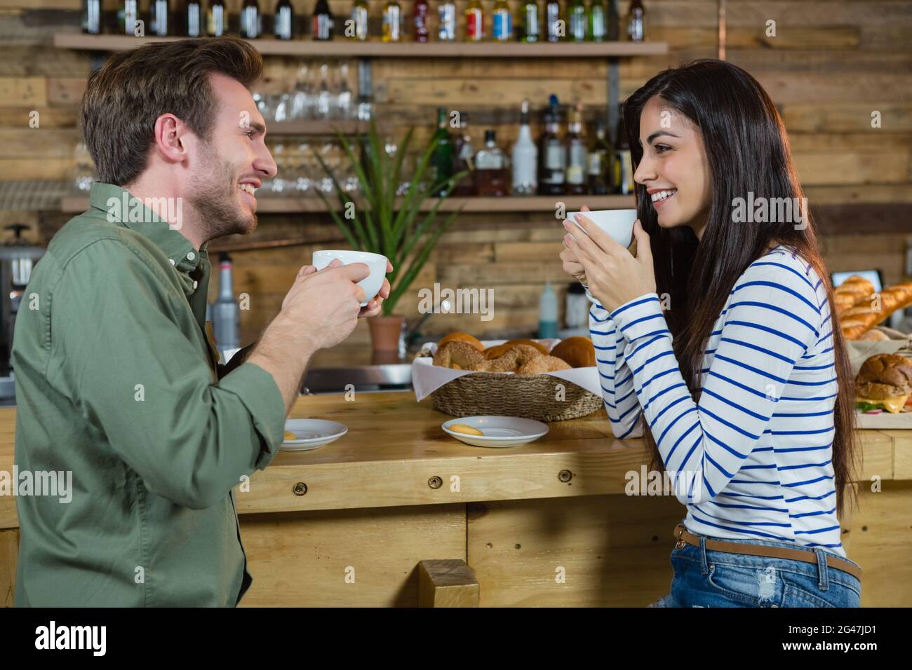 Couple interacting each other while having coffee at counter Stock Photo