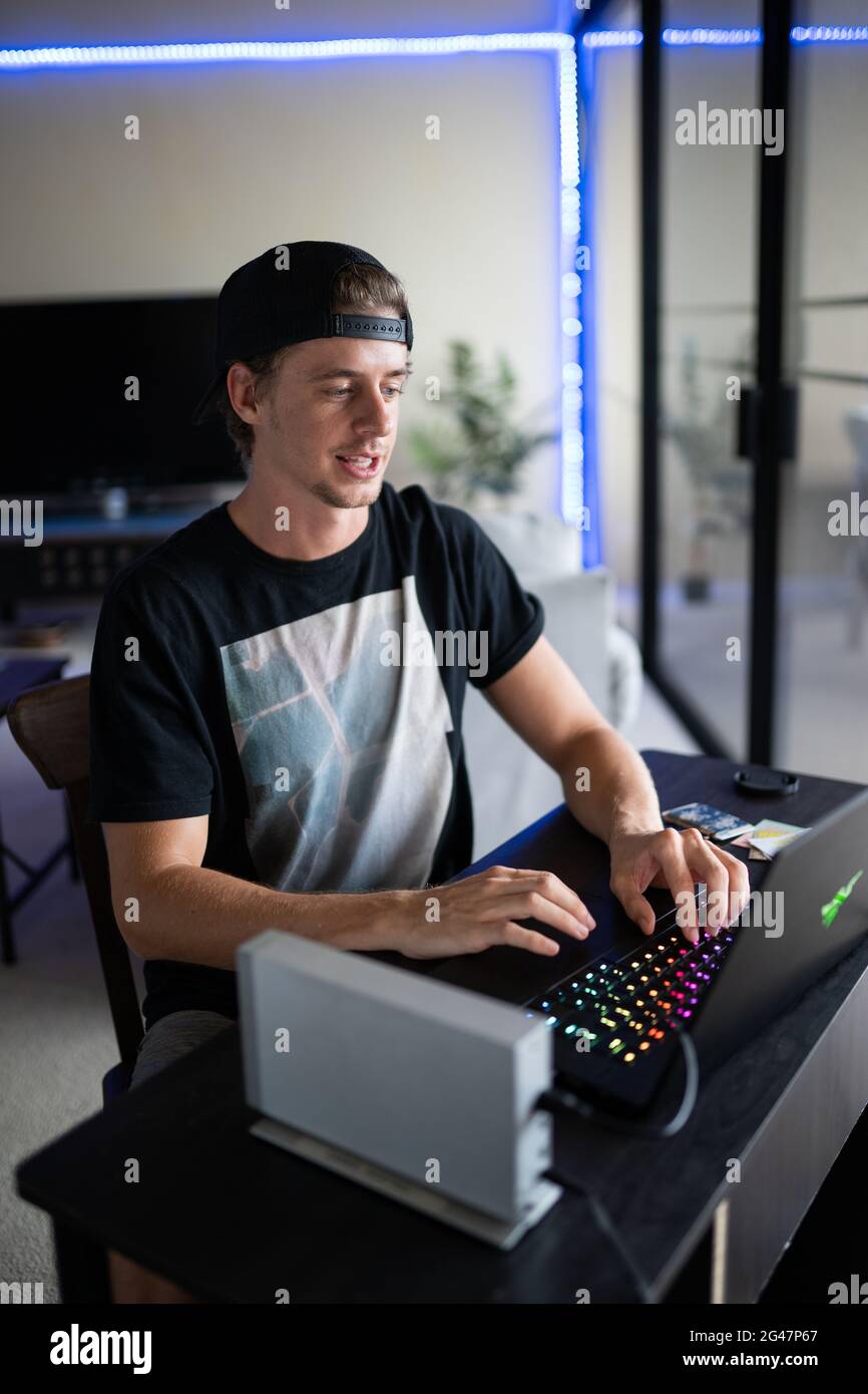 Vertical shot of a young American dude gaming on his ultrapowerful laptop  in his house Stock Photo - Alamy