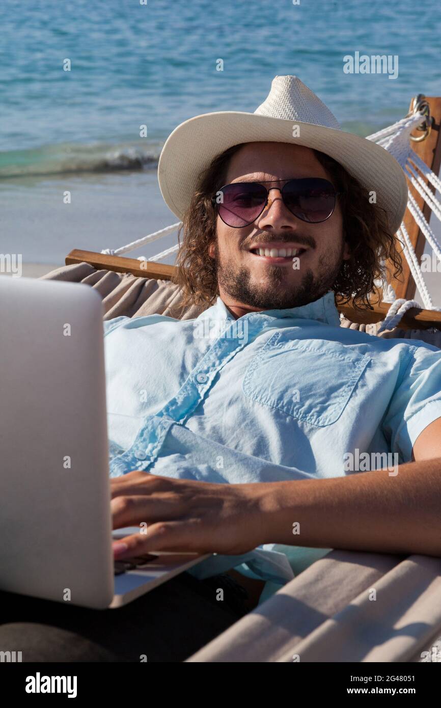 Man using laptop while relaxing on hammock Stock Photo