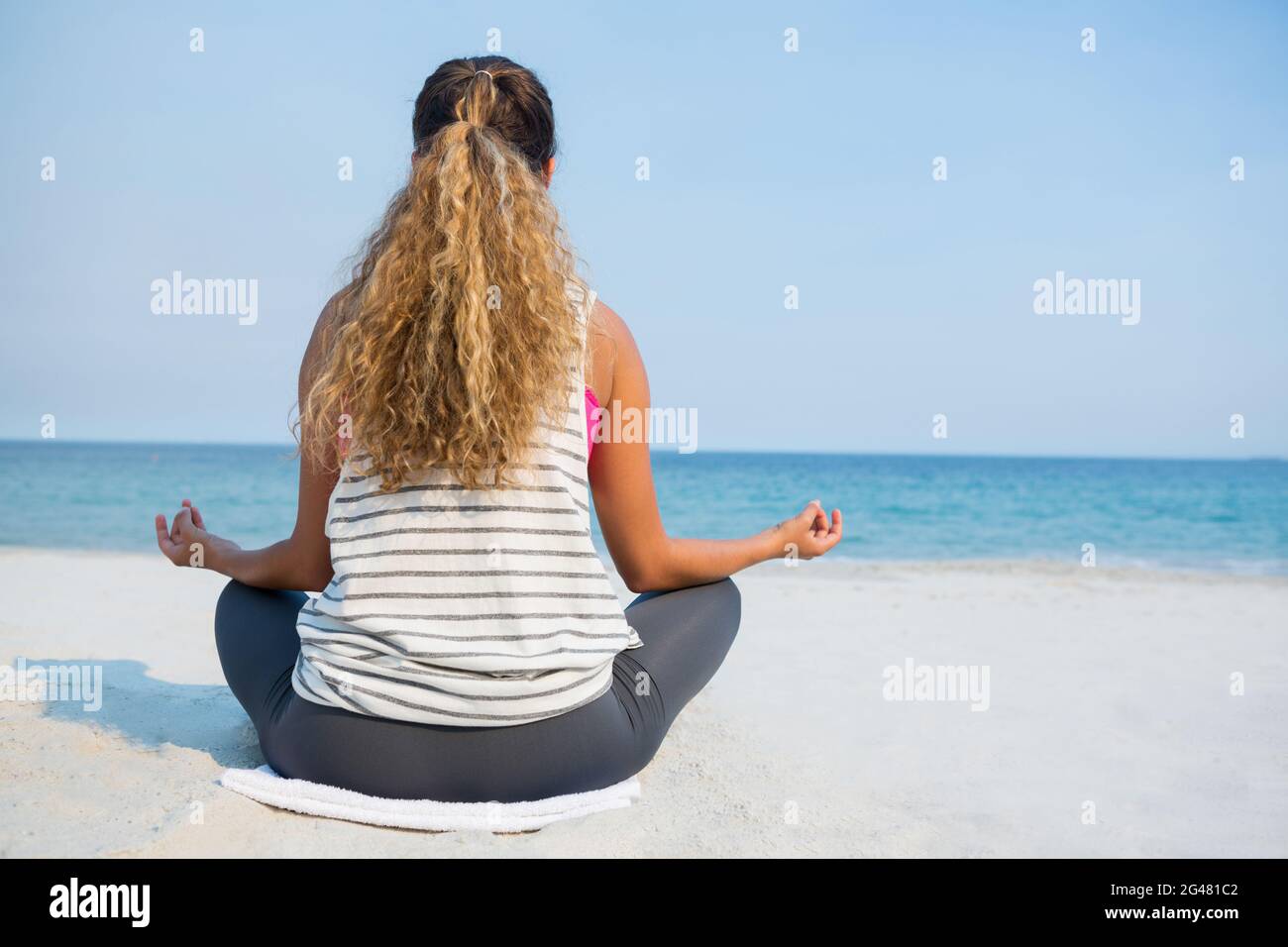 Rear view of woman sitting on beach meditating hi-res stock photography ...