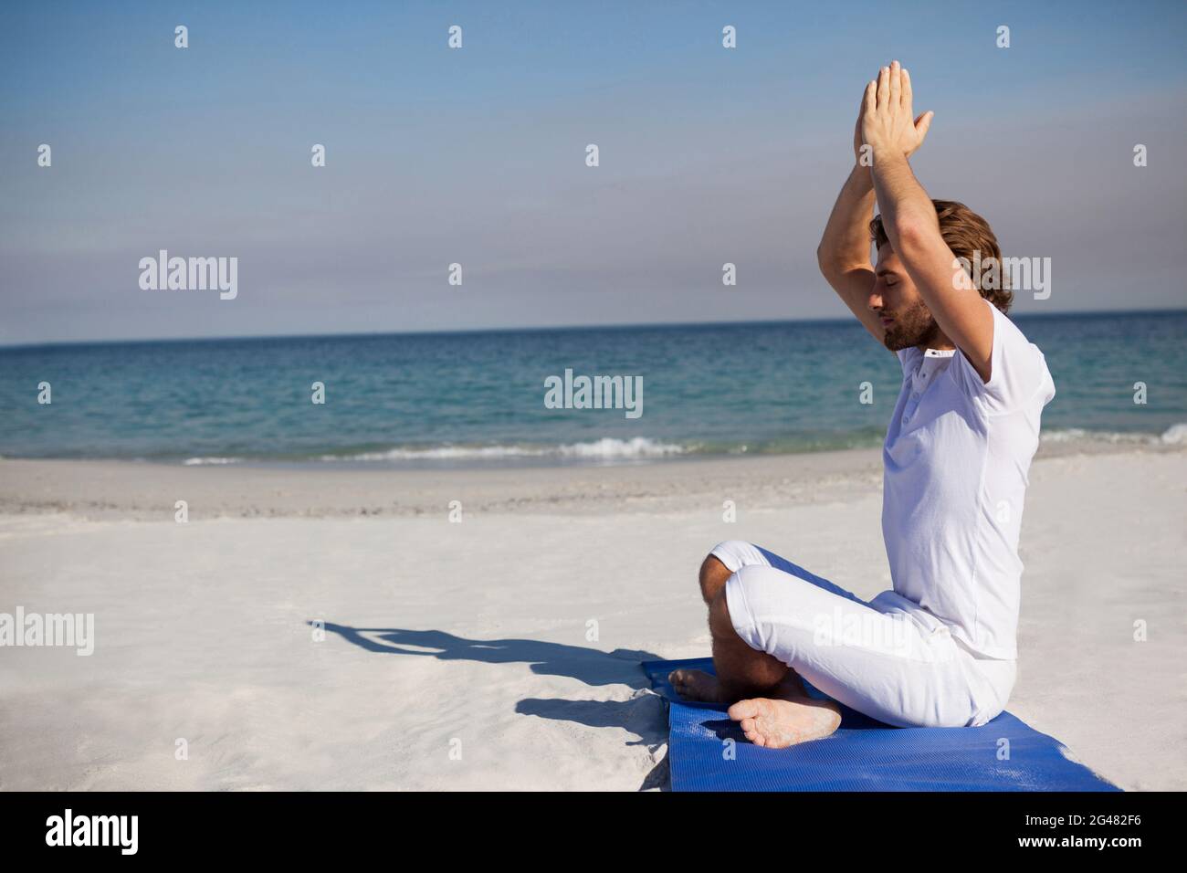 Side view of man meditating at beach Stock Photo - Alamy