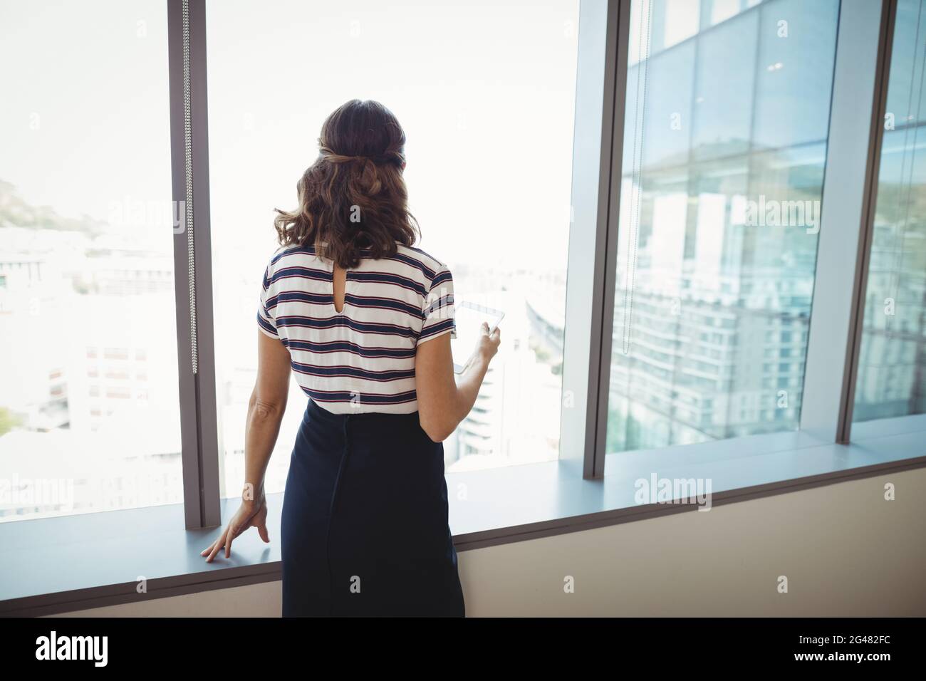 Thoughtful executive standing near window Stock Photo