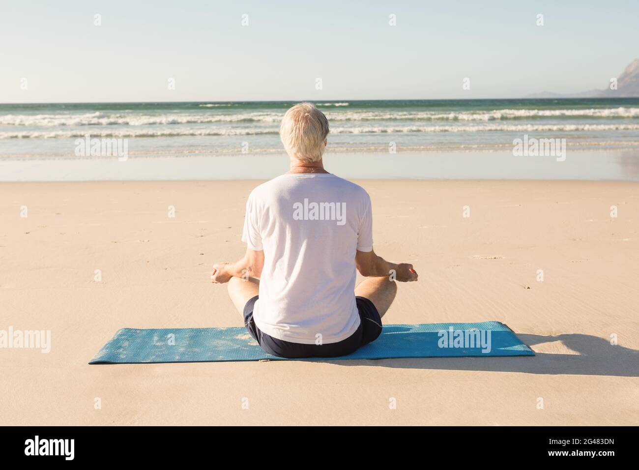 Rear view of senior man meditating at beach Stock Photo - Alamy