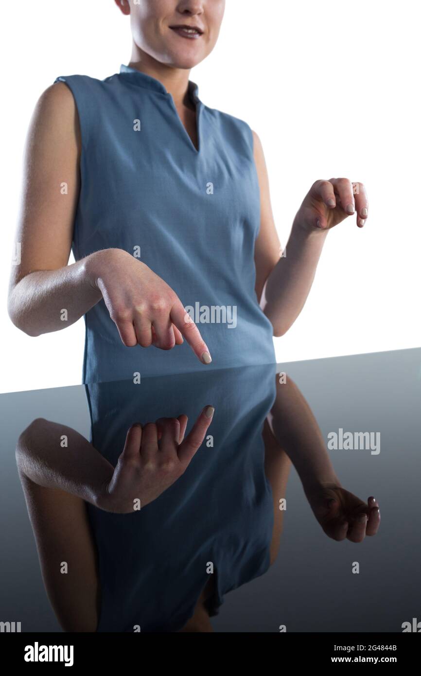 Mid section of smiling businesswoman using imaginary interface at table Stock Photo