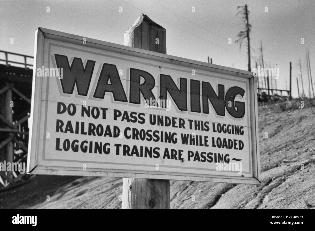 Warning - Do Not Pass Under This Logging Railroad Crossing While Loaded Logging Trains Are Passing Sign, Tillamook County, Oregon - October 1941 Stock Photo
