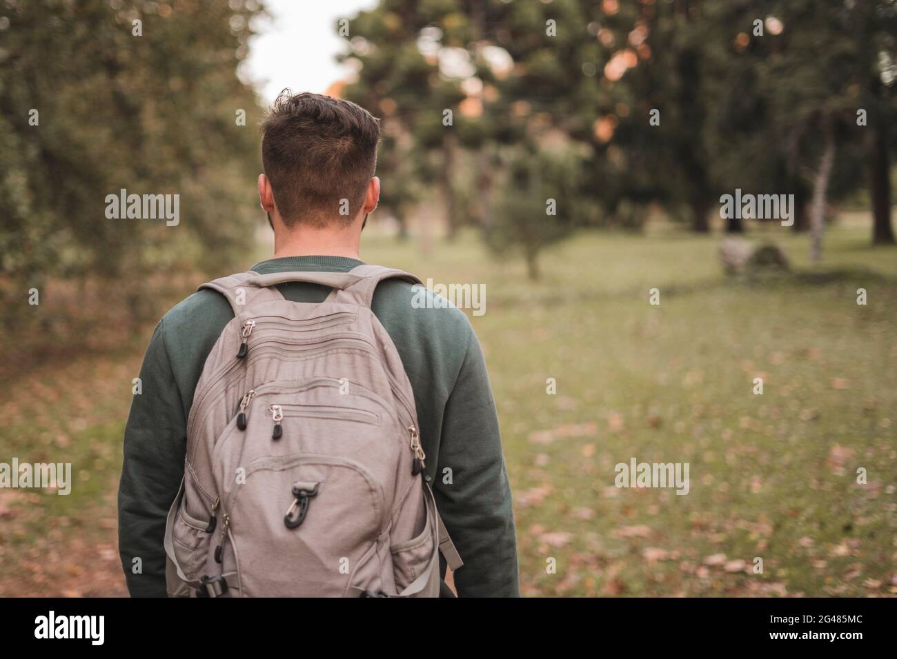 Young man walking in a park with a backpack on his back Stock Photo - Alamy