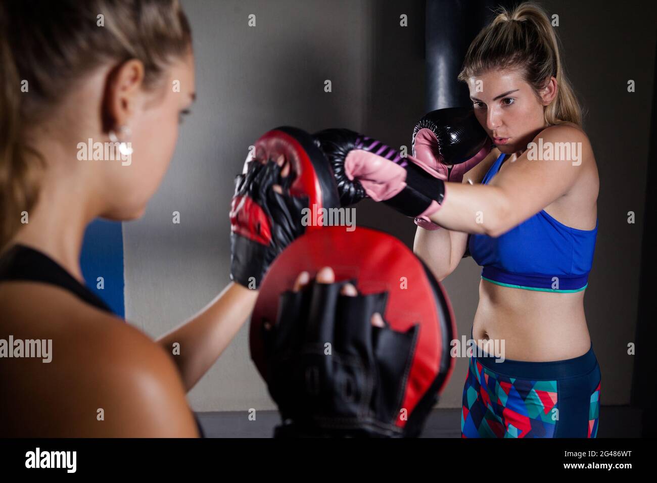 Trainer assisting woman in boxing Stock Photo