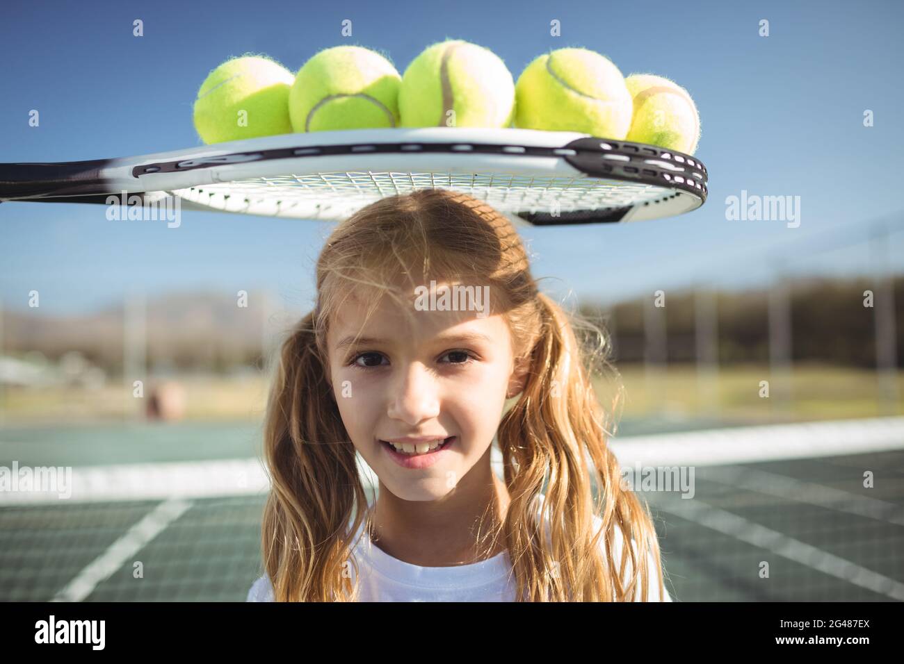 Smiling girl standing below tennis racket and balls Stock Photo Alamy