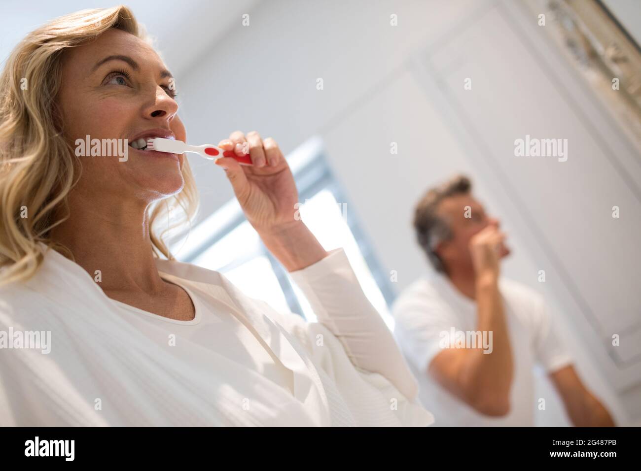 Couple brushing teeth in bathroom Stock Photo