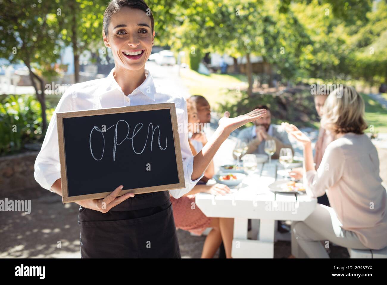 Smiling waitress standing with open sign board Stock Photo