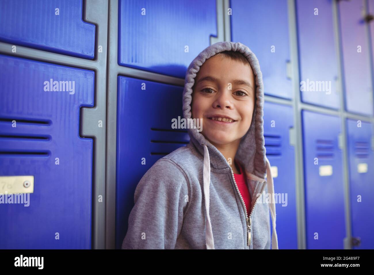 Portrait of smiling boy standing by lockers Stock Photo