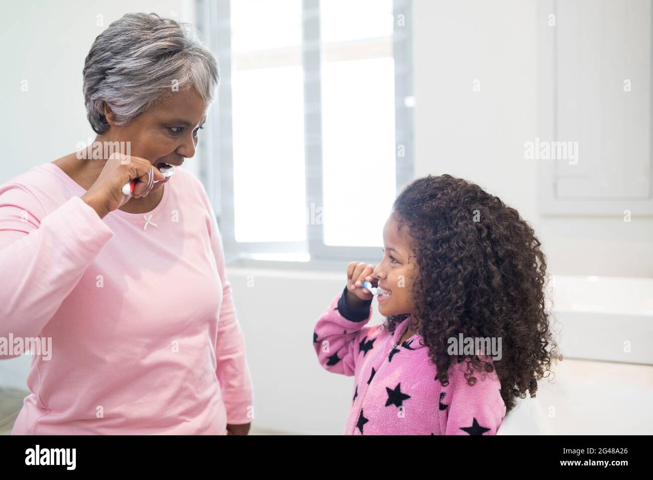 Grandmother and granddaughter brushing teeth in the bathroom Stock Photo