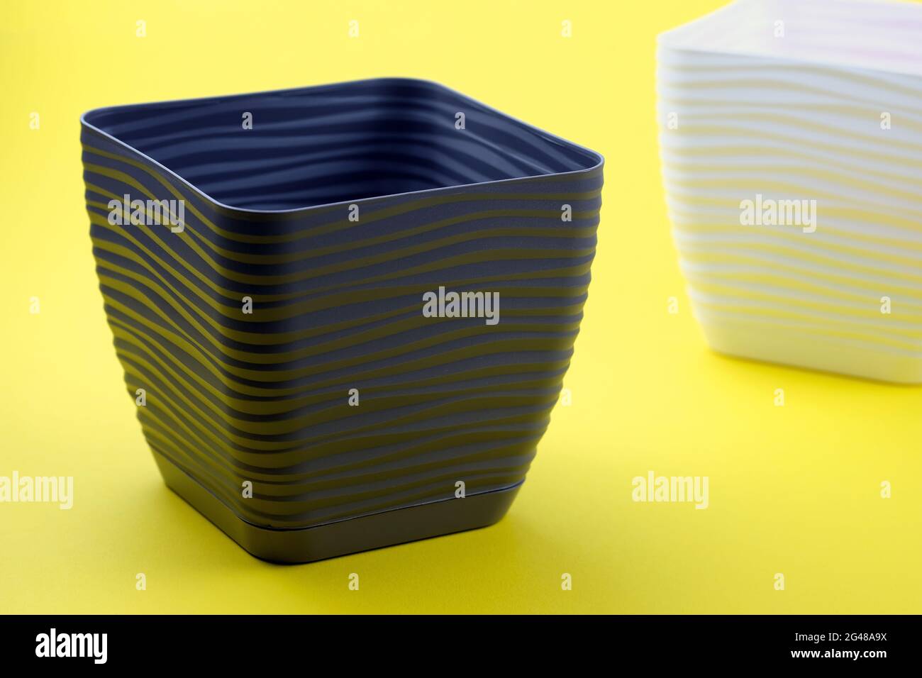 Empty plastic flower pot on a yellow background. Square flower
