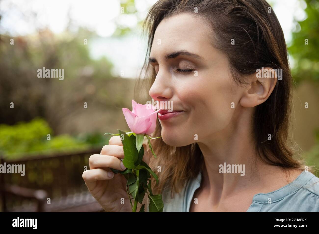Close-up of beautiful woman with eyes closed smelling pink rose Stock Photo