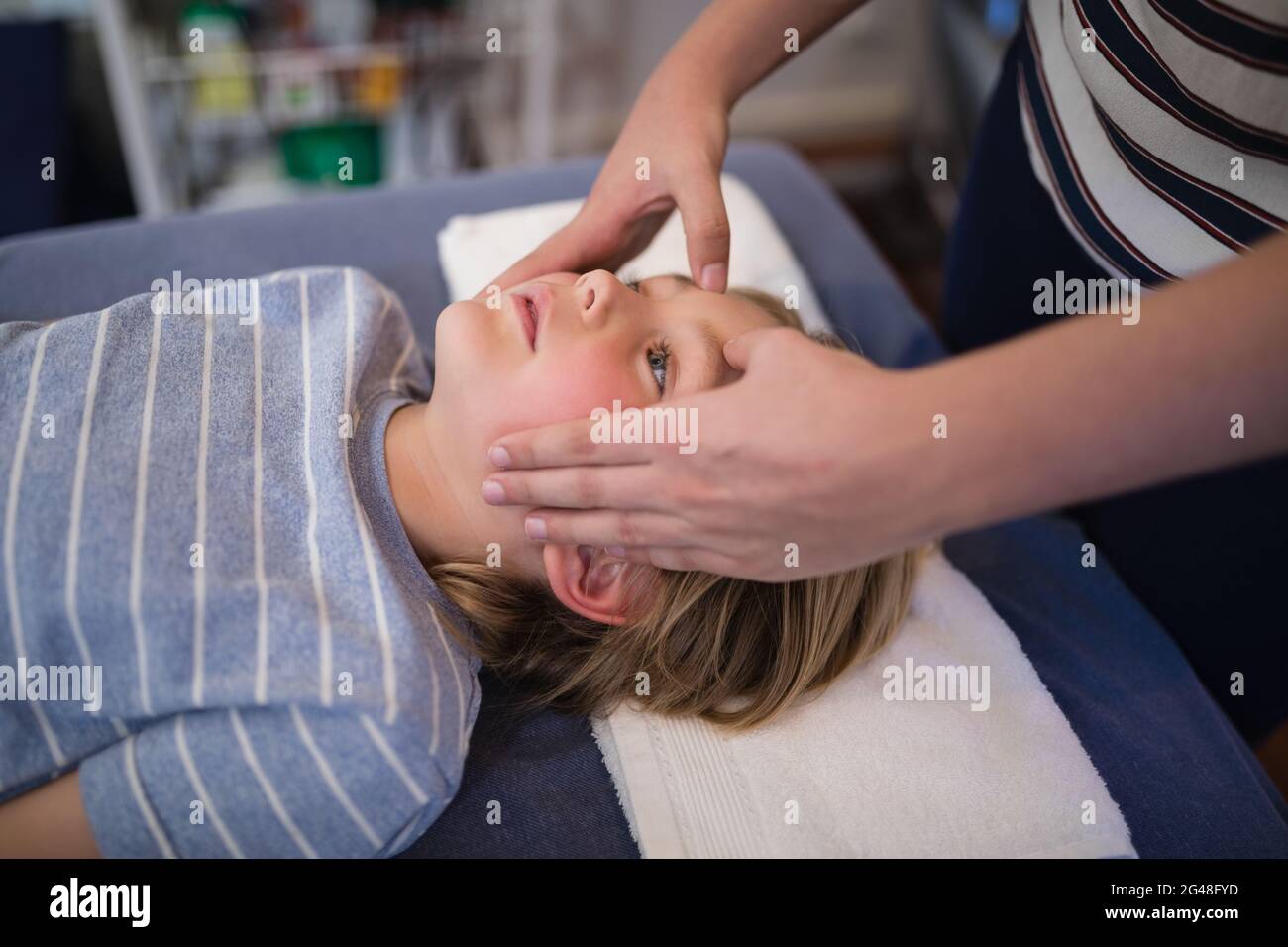 Midsection of female therapist giving head massage to boy lying on bed  Stock Photo - Alamy