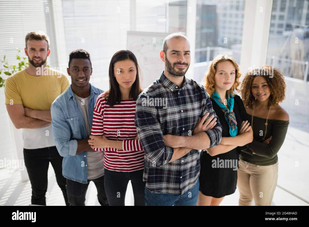 Business executives standing with arms crossed in office Stock Photo