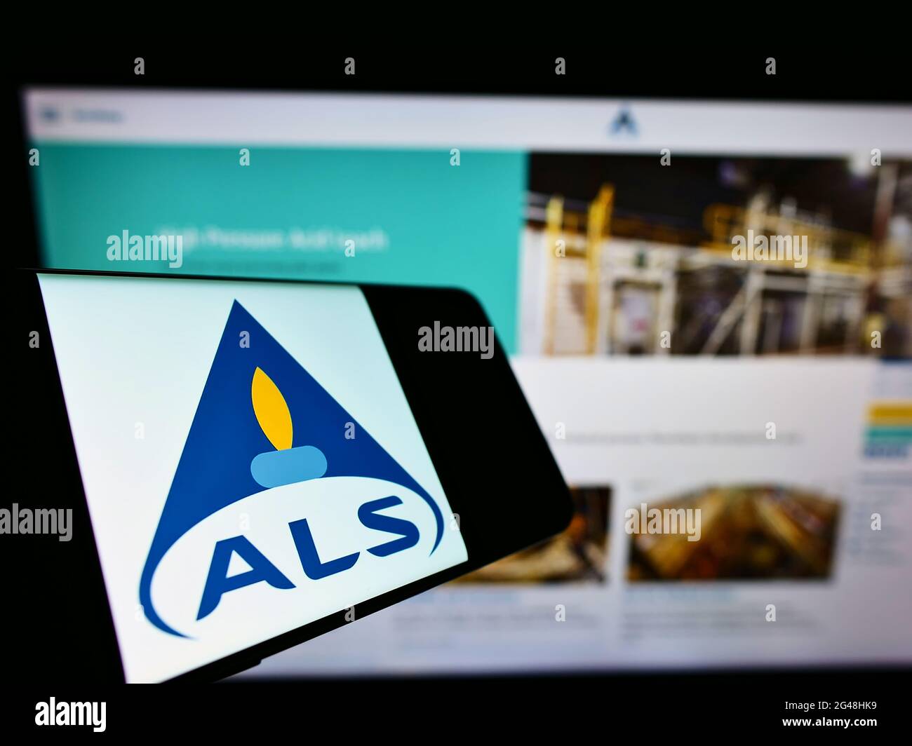 Smartphone with logo of Australian testing services company ALS Limited on screen in front of website. Focus on center-right of phone display. Stock Photo