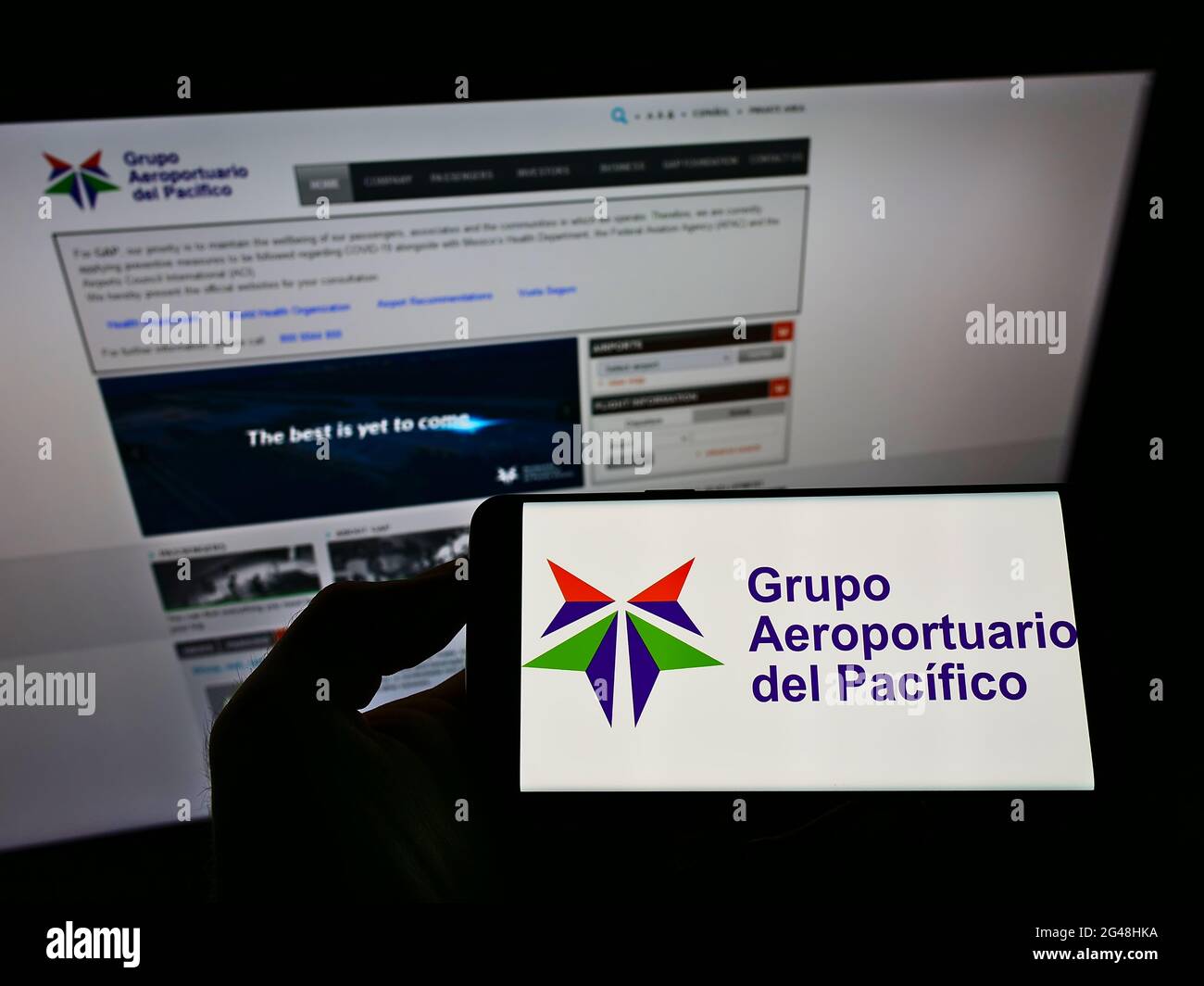 Person holding smartphone with logo of airport operator Grupo ...