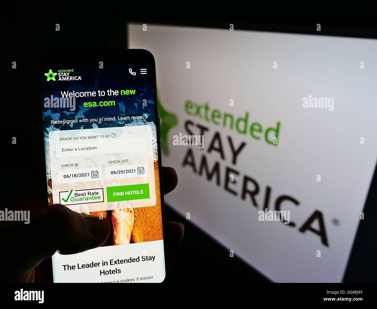 Person holding smartphone with website of US apartment hotel chain Extended Stay America Inc. on screen with logo. Focus on center of phone display. Stock Photo