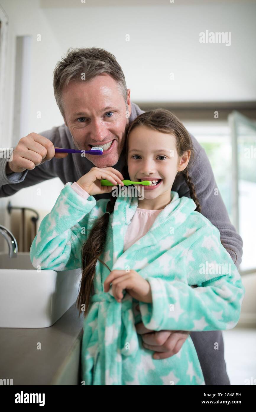 Smiling father and daughter brushing teeth in bathroom Stock Photo