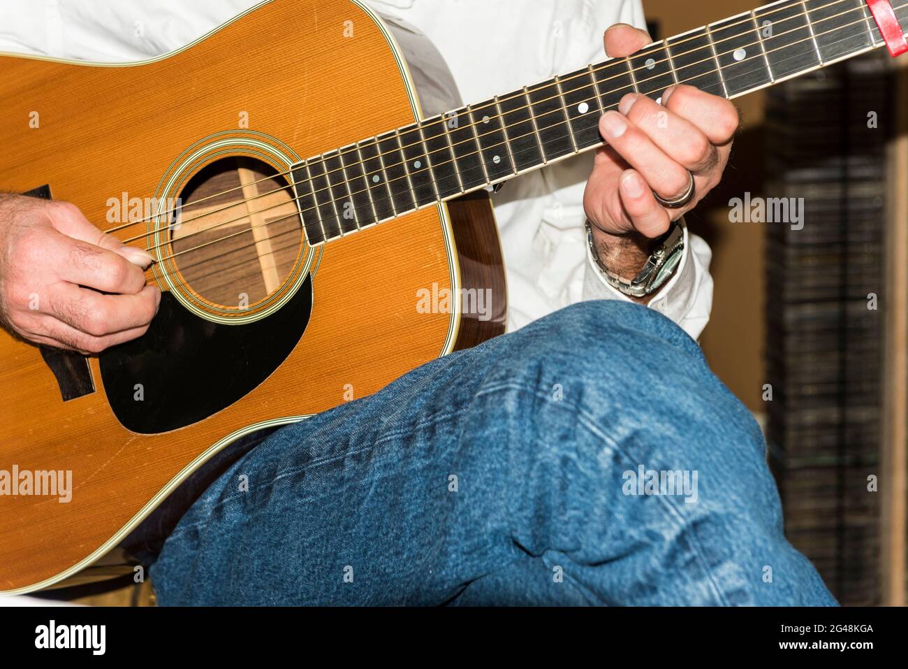 Detail of seated male guitarist finger picking a Vintage MartinD 35  accustic guitar. Stock Photo