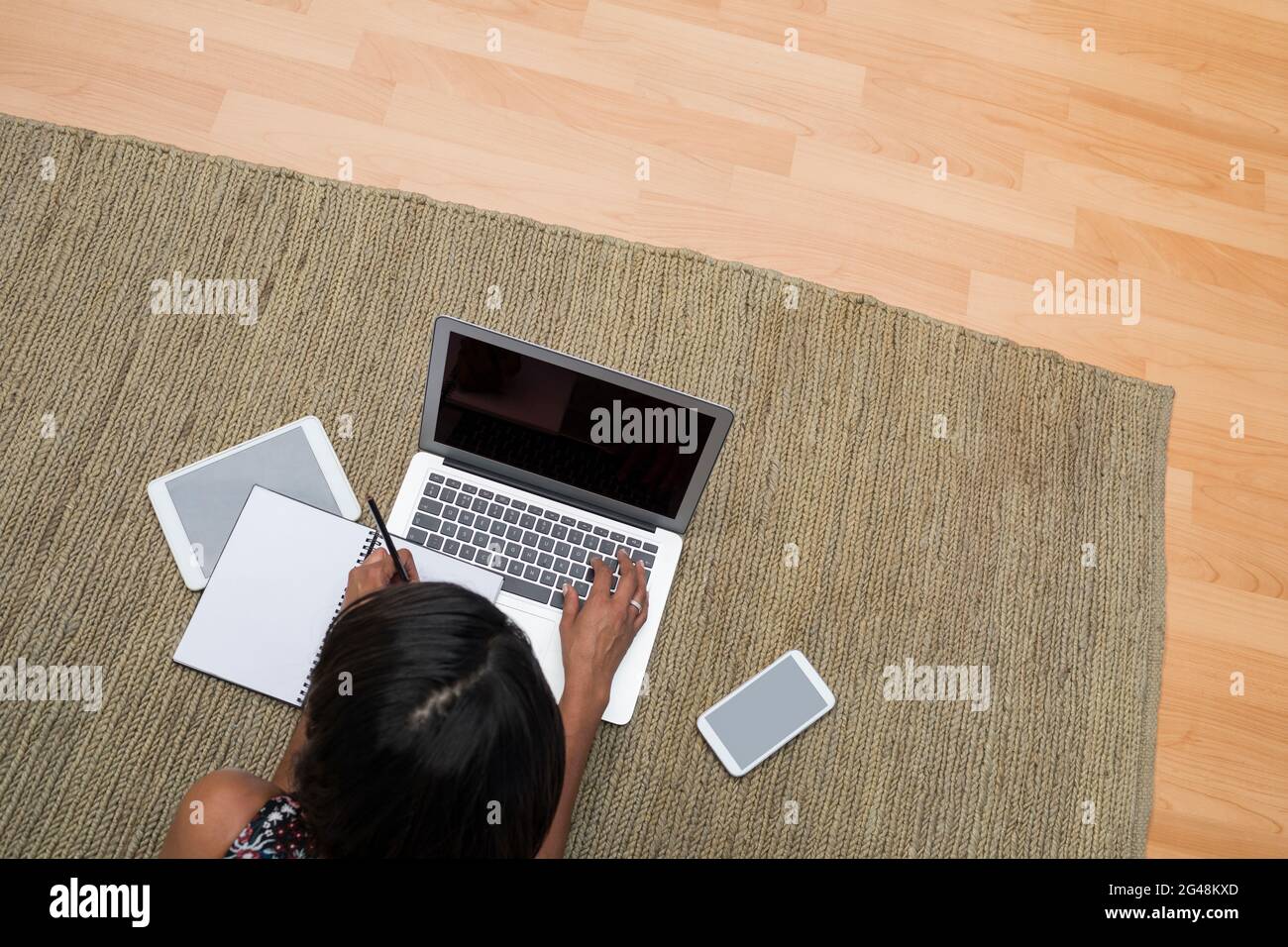 Female executive using laptop while lying on carpet Stock Photo - Alamy