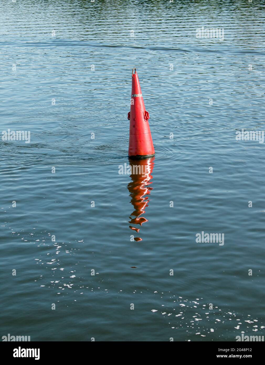Floating red navigational buoy on blue water of Dnipro River. Buoy in