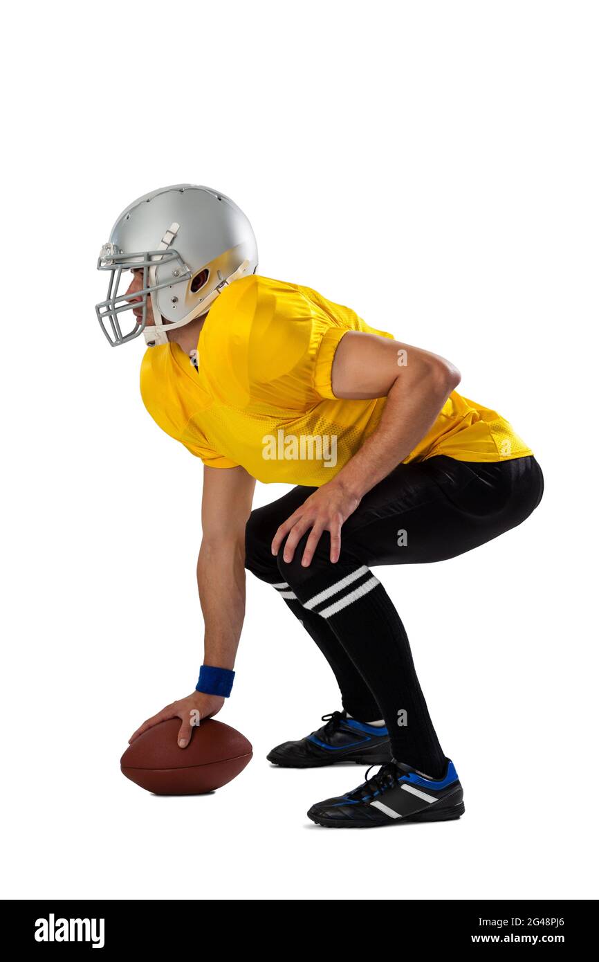 Side view of determined American football player bending with ball