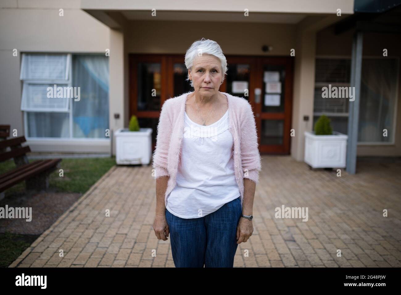 Portrait of serious senior woman standing on entrance Stock Photo