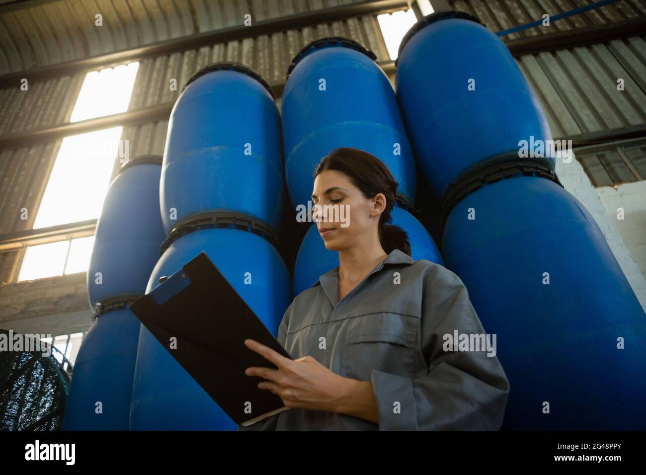 Female worker writing on clipboard in olive factory Stock Photo - Alamy