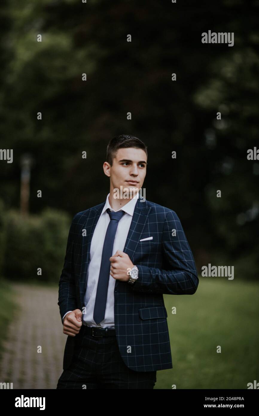 Caucasian young businessman in a suit and tie standing in the park ...
