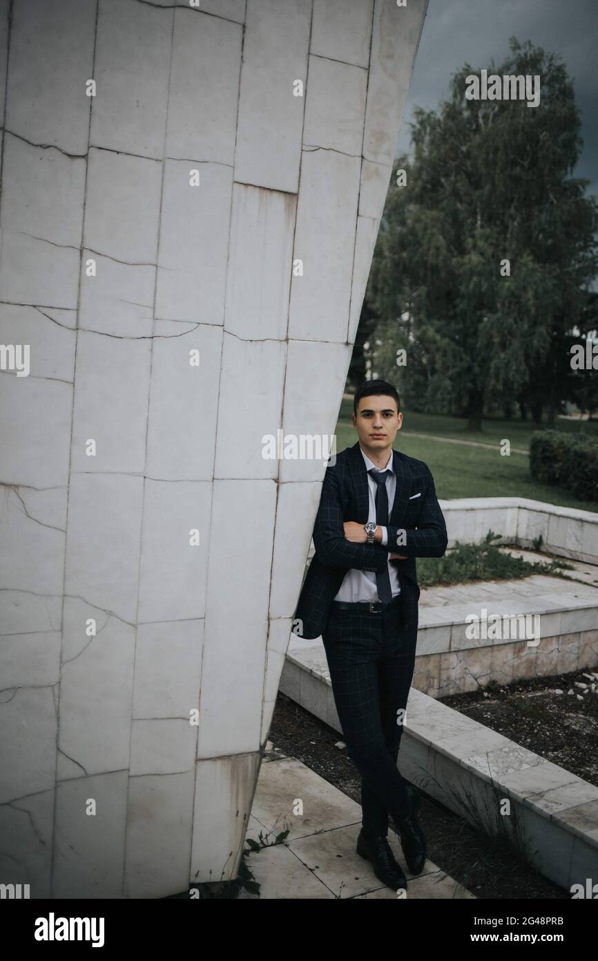 Caucasian young businessman in a suit and tie standing in the park ...