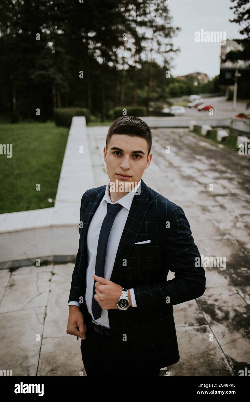 Caucasian young businessman in a suit and tie standing in the park ...