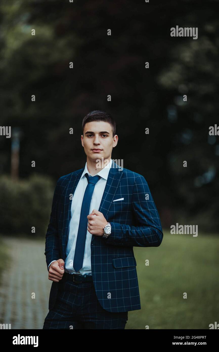 Caucasian young businessman in a suit and tie standing in the park ...