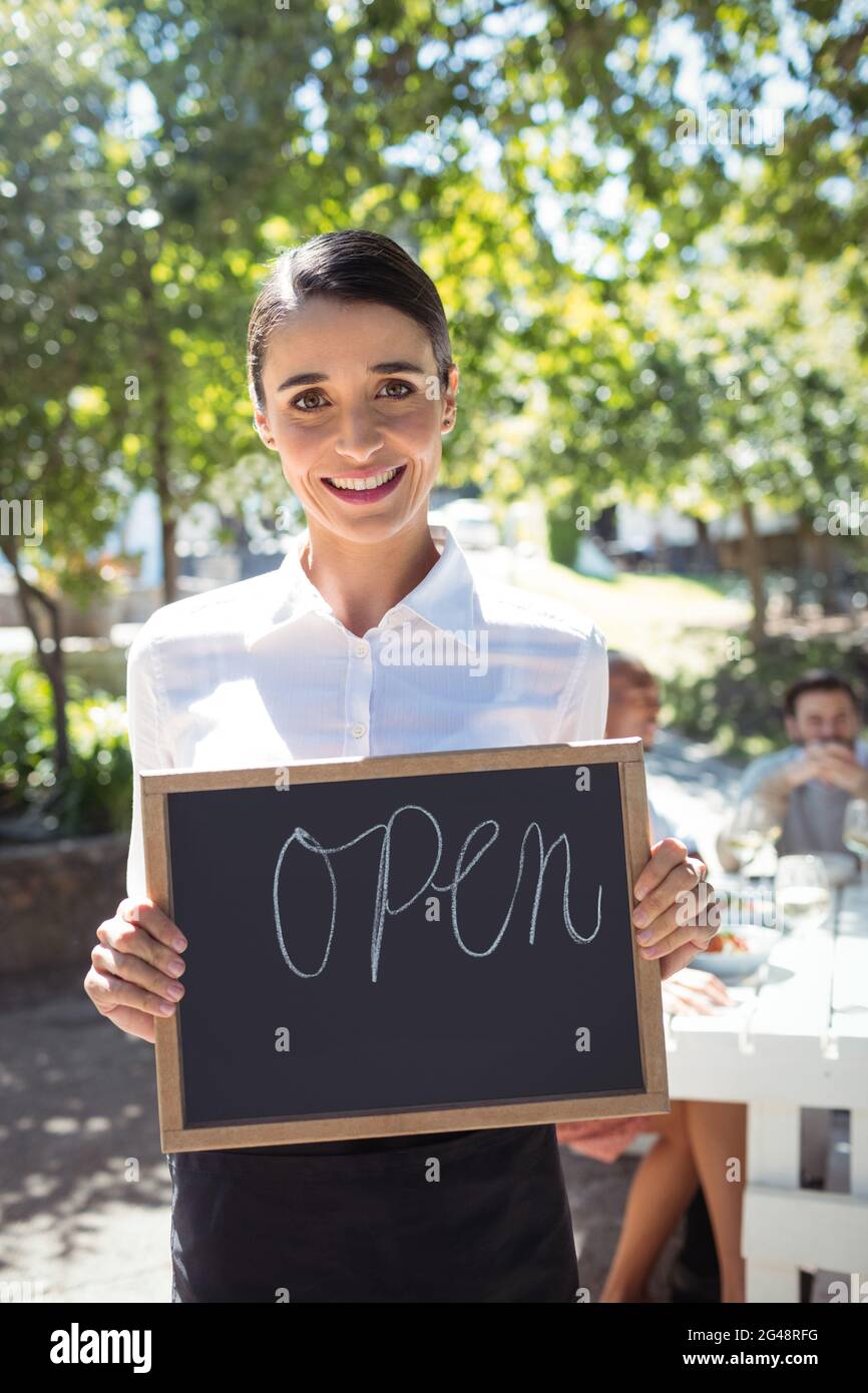 Smiling waitress standing with open sign board Stock Photo