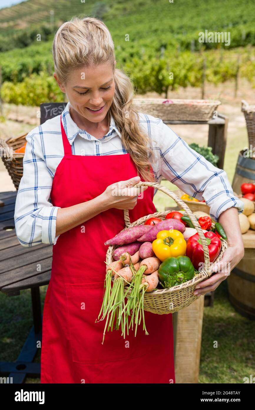 Woman holding a basket of fresh vegetables at stall Stock Photo - Alamy