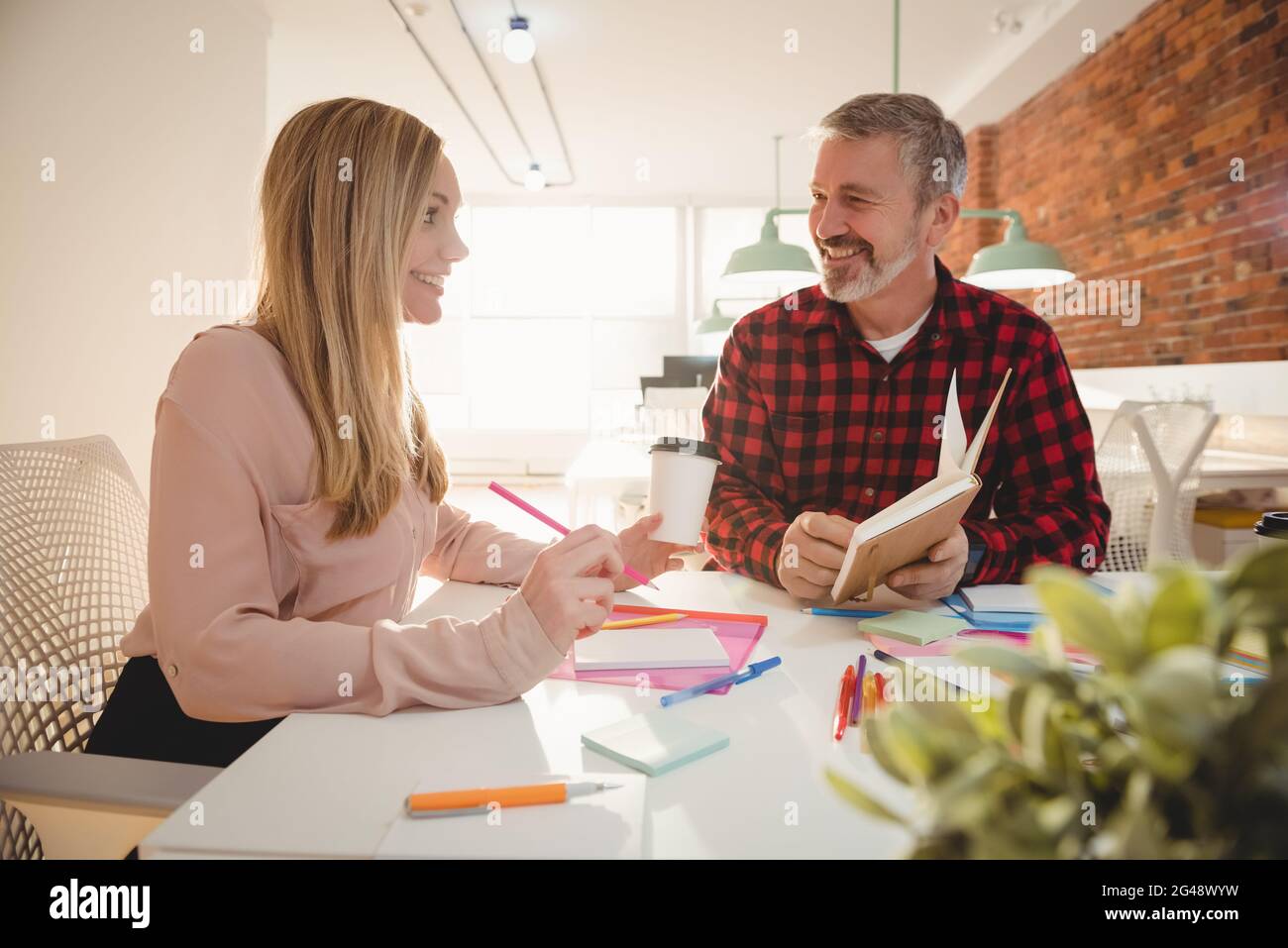 Smiling executives discussing over diary Stock Photo
