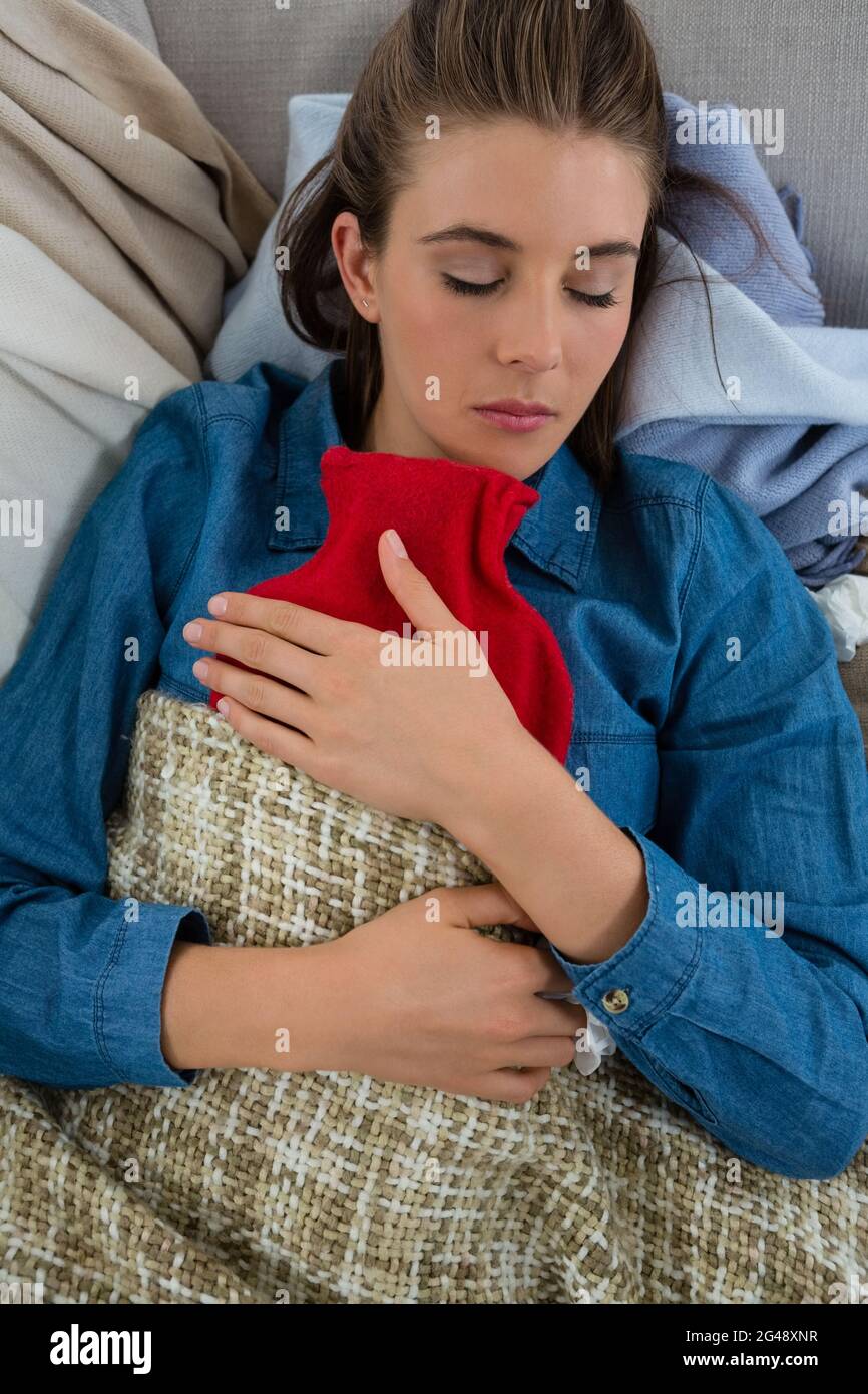 Directly above shot of woman with hot water bottle while sleeping Stock