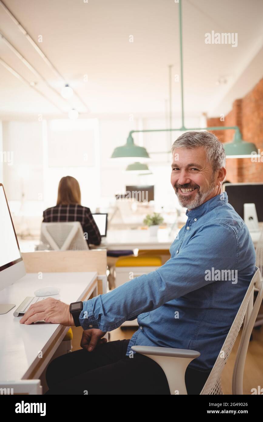 Portrait of smiling male executive sitting at desk Stock Photo - Alamy