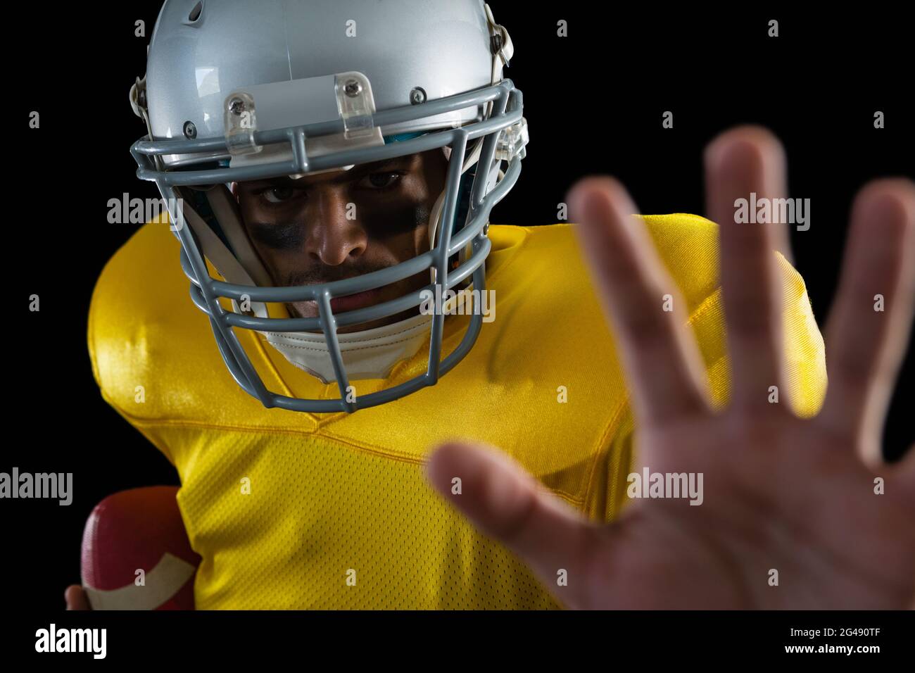 American football player holding a ball and gesturing a hand stop sign ...