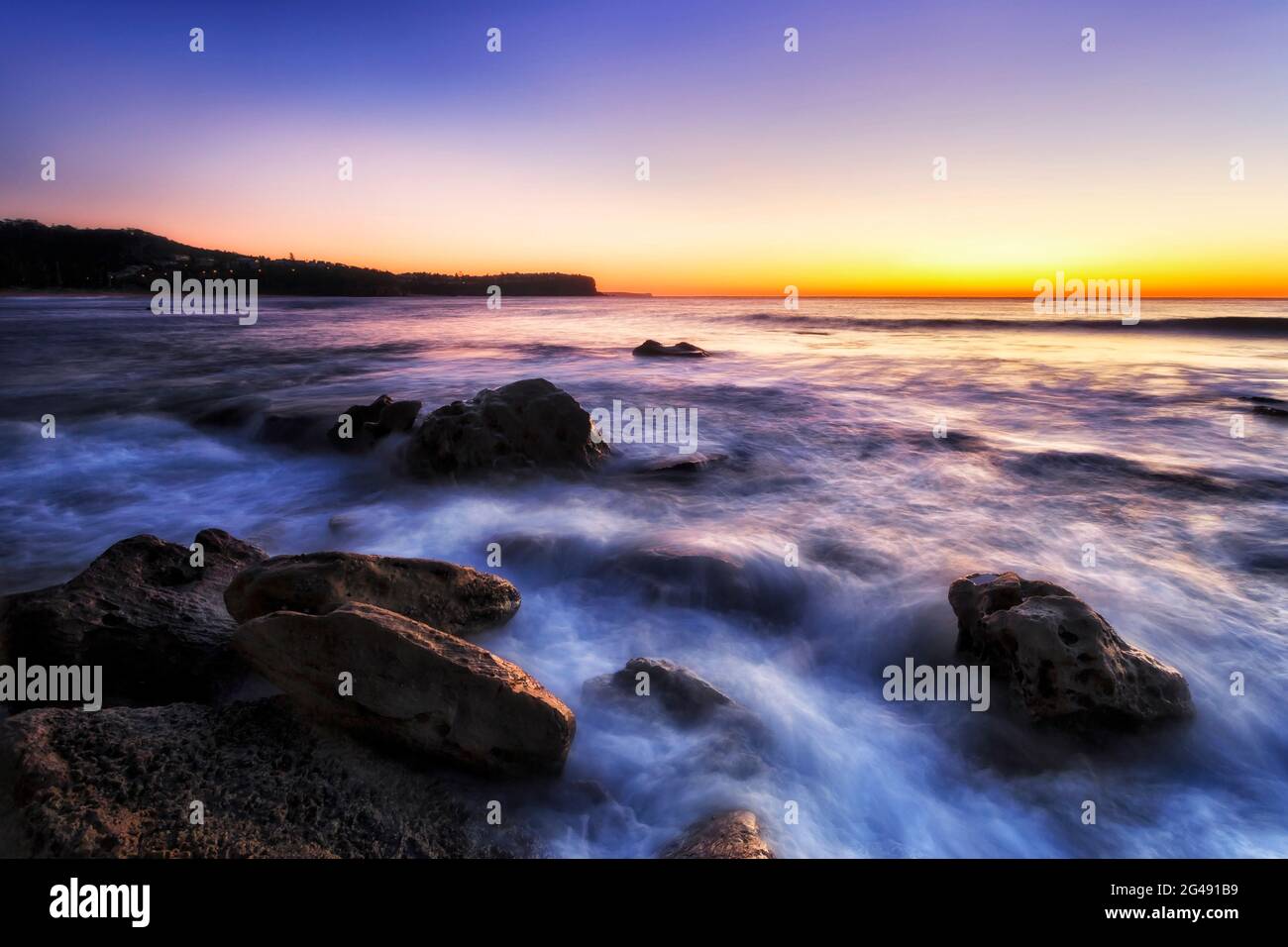 Sandstone rocks on Sydney Northern beaches Newport beach facing Pacific ocean and rising sun. Stock Photo