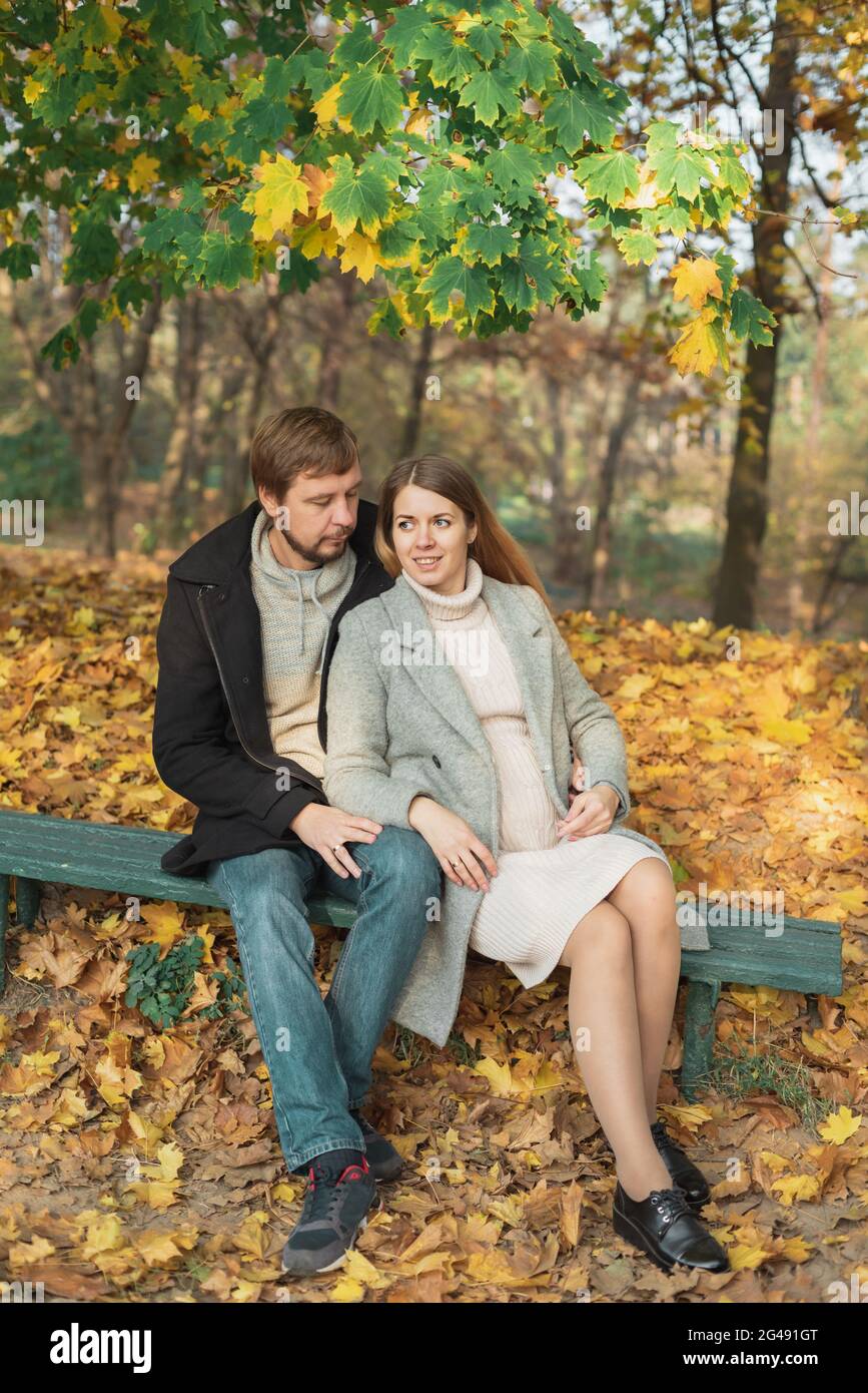 Family together in autumn park. Happy couple Husband and his pregnant wife relaxing in nature. happy married couple expecting baby. Pregnancy, materni Stock Photo