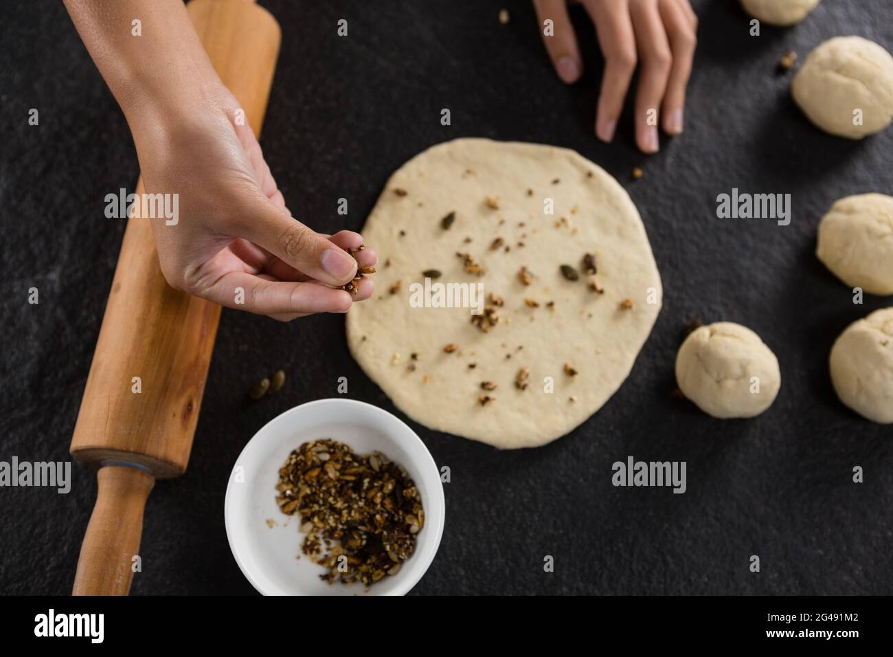 Woman adding dry fruits over flattened dough Stock Photo Alamy