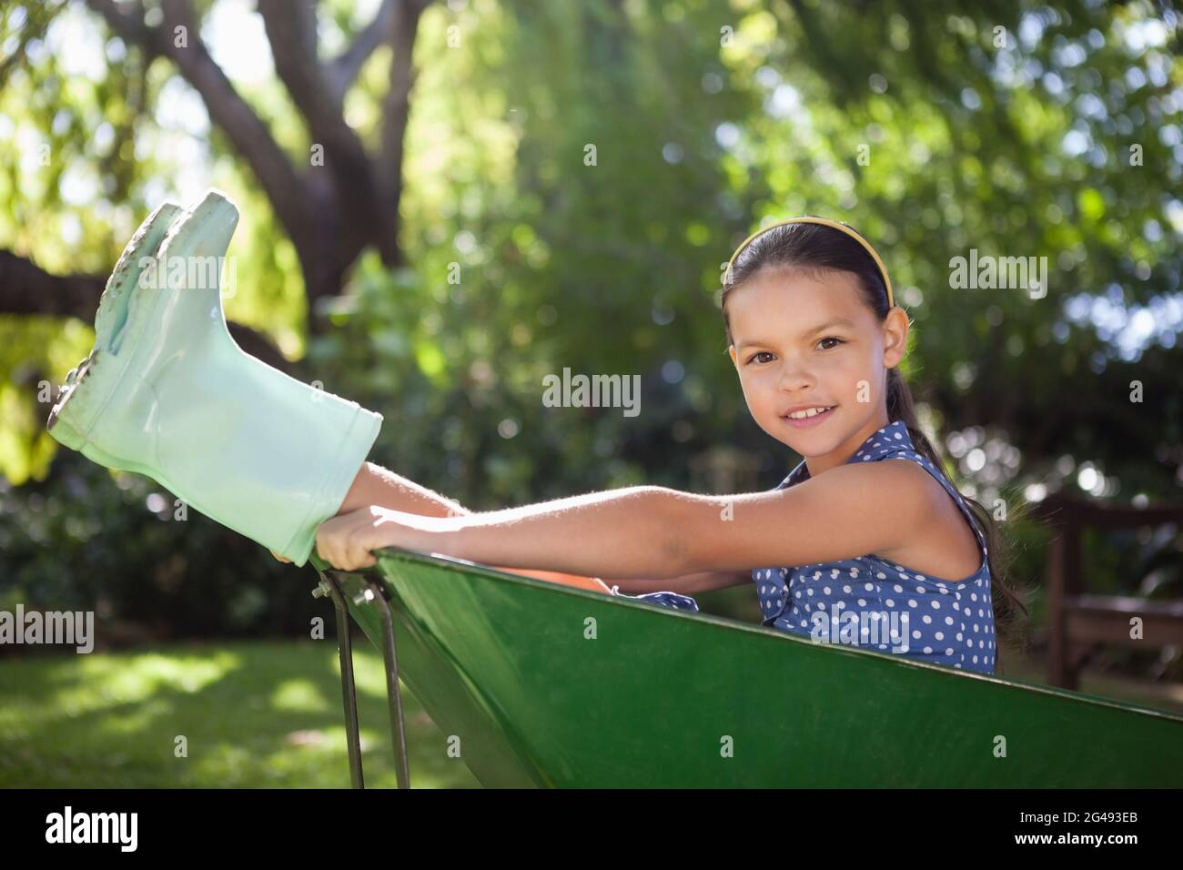 Portrait of girl sitting in wheelbarrow at backyard Stock Photo - Alamy